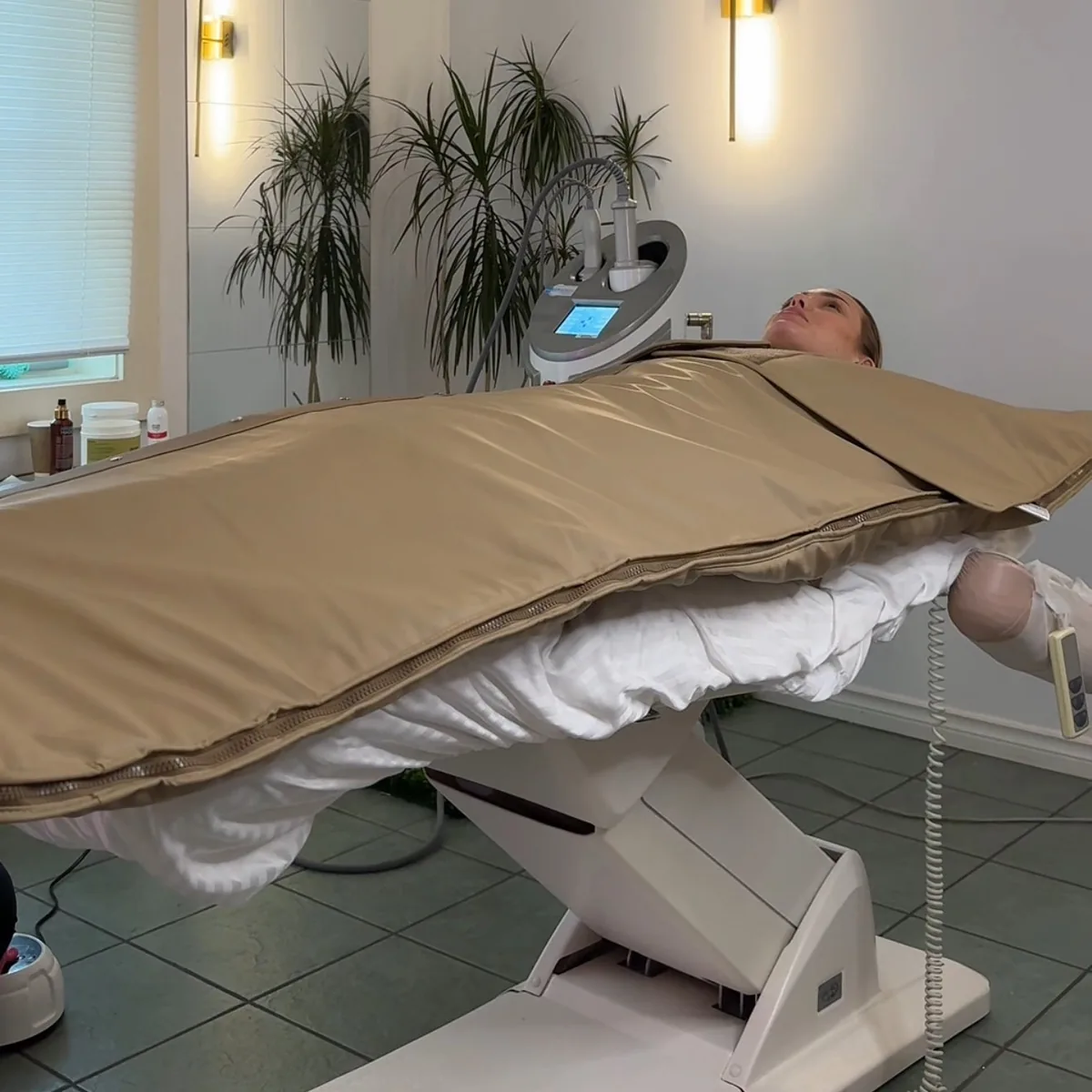 Luxury infrared sauna blanket in use on a treatment bed, with the control unit beside it.
